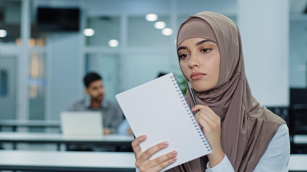 Femme indienne du millénaire réfléchie en hijab regardant de côté la planification de la préparation de la réunion