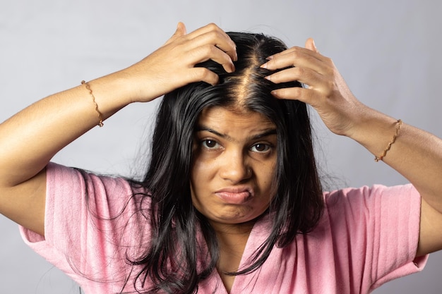 Une femme indienne inquiète à cause du problème de perte de cheveux tient le cuir chevelu sur un fond blanc
