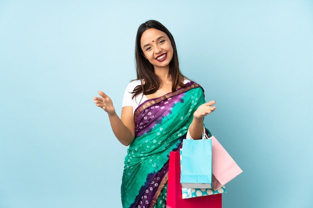 Femme indienne avec des sacs à provisions présentant et invitant à venir avec la main