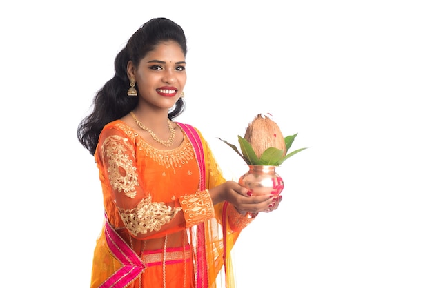 Femme indienne tenant un Kalash en cuivre traditionnel avec feuille de noix de coco et de mangue avec décoration florale, essentiel dans le festival hindou indien et culte