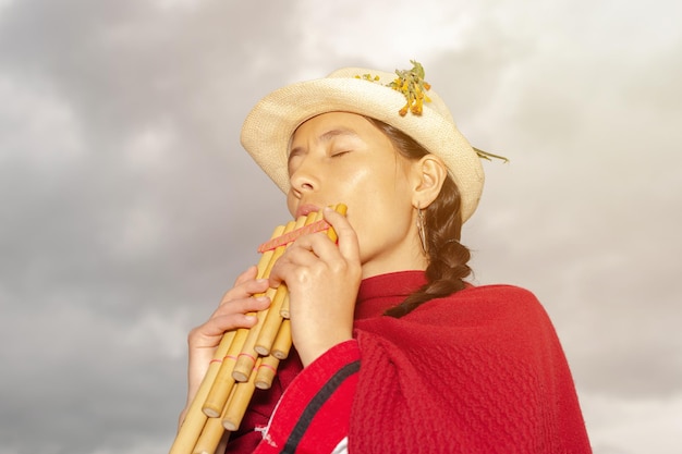 Photo femme indigène latino-américaine habillée traditionnellement jouant de la zampona les yeux fermés