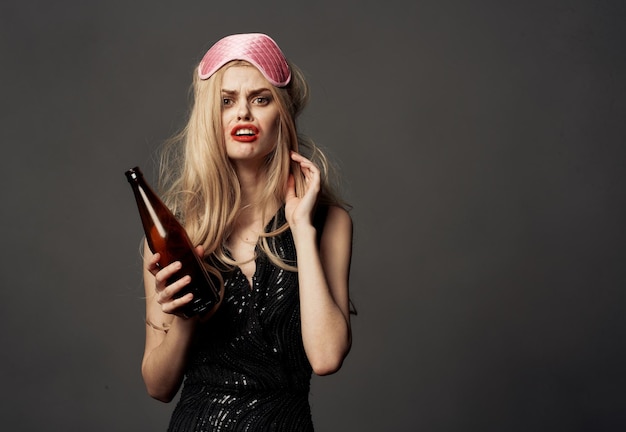 Une femme indigne avec une bouteille de bière et un masque rose sur la tête d'un modèle blond photo de haute qualité