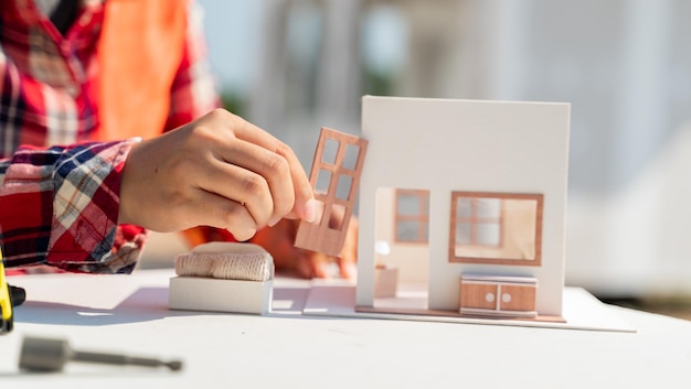 Femme d'ingénierie et d'architecte travaillant avec un modèle de maison sur le site de la propriété de construction.