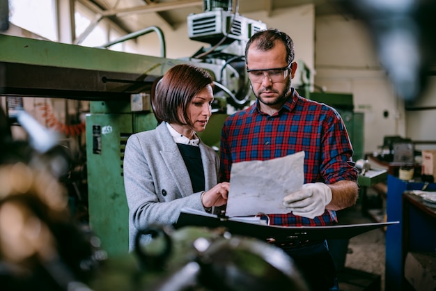 Femme ingénieure debout avec machiniste et analyse de plan