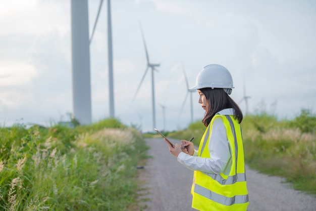 Femme ingénieure travaillant et tenant le rapport à la centrale éolienne de la centrale électrique sur la montagneThaïlande