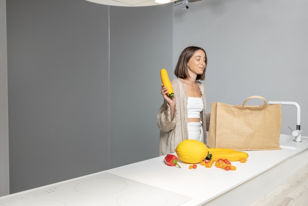 Femme avec des ingrédients crus dans une cuisine moderne à la maison