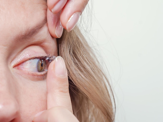 La femme insère une lentille de contact dans l'oeil