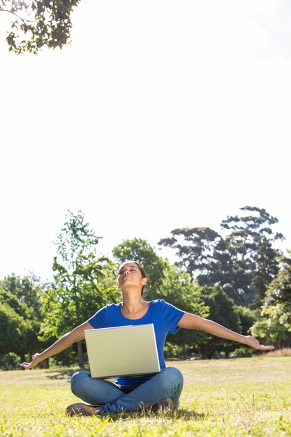 Femme insouciante utilisant un ordinateur portable dans le parc