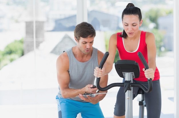 Femme avec un instructeur de sexe masculin travaillant à la classe de spinning