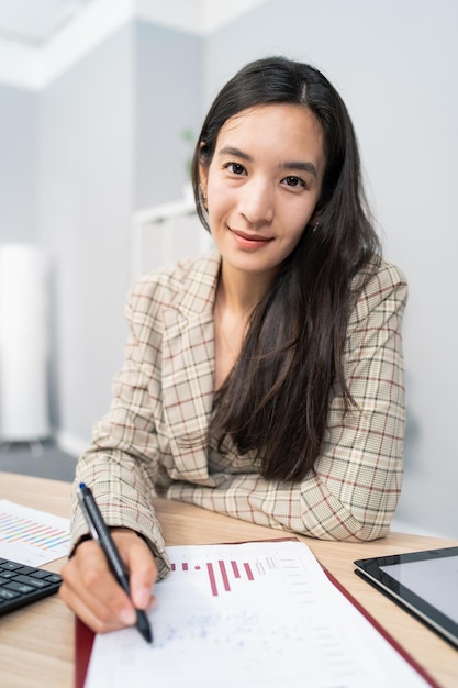 Une femme intelligente travaillant dans le marketing d'analyse financière calcule les bénéfices de l'entreprise est assise au bureau