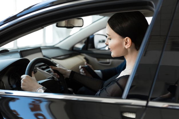 Femme à l'intérieur d'une voiture chez un concessionnaire automobile