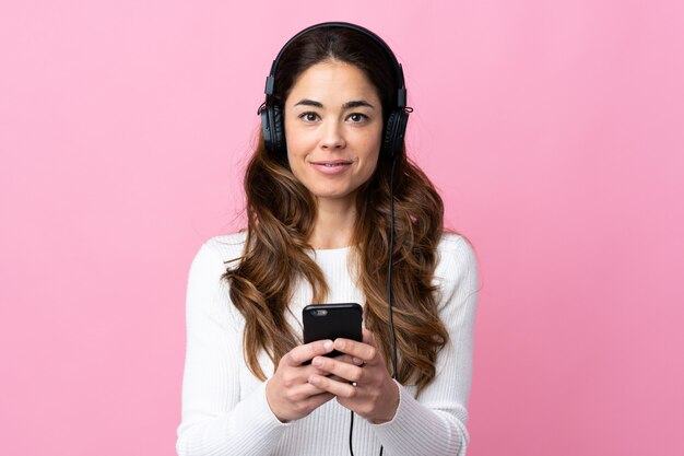 Femme, isolé, rose, mur, écoute, musique, mobile, regarder, devant