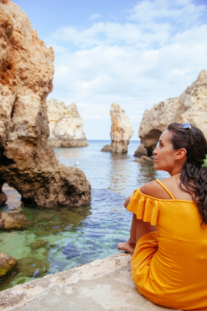 Femme isolée en vacances en Algarve entourée de falaises et de mer