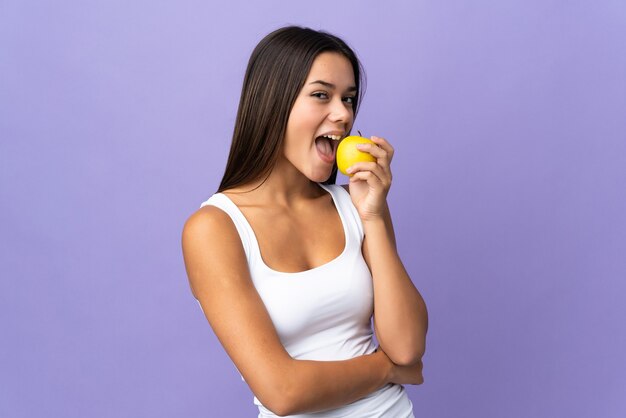 femme isolée sur violet mangeant une pomme