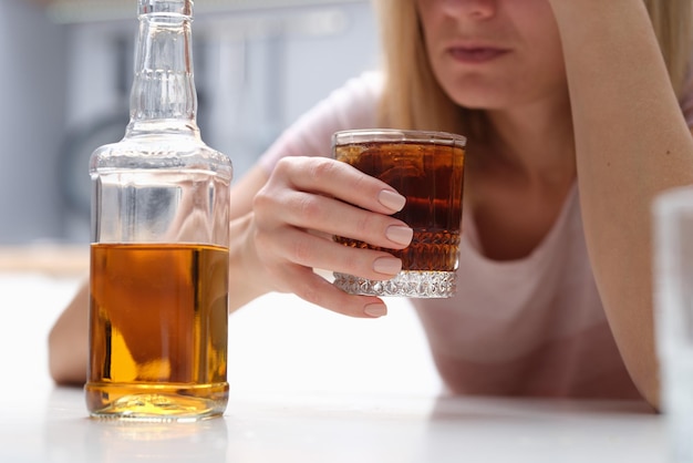 Femme ivre tenant un verre de whisky et d'alcooliques seuls