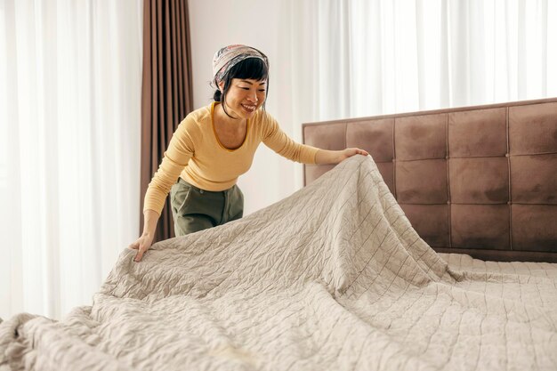 Photo une femme japonaise bien rangée fait son lit dans une chambre.