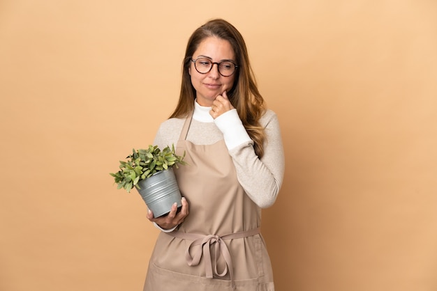 Femme de jardinier d'âge moyen tenant une plante isolée