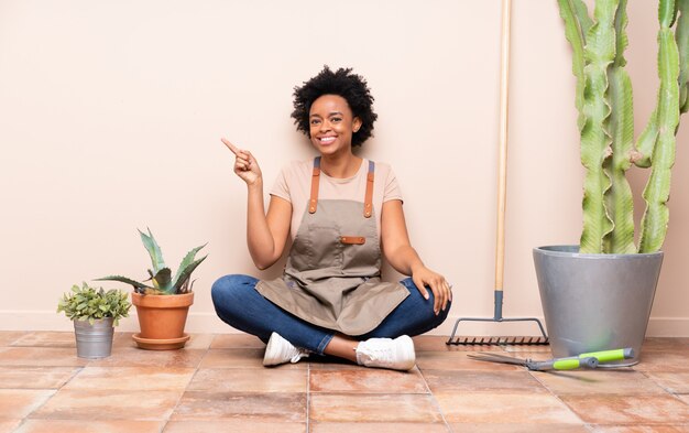 Femme jardinier assis sur le sol autour des plantes