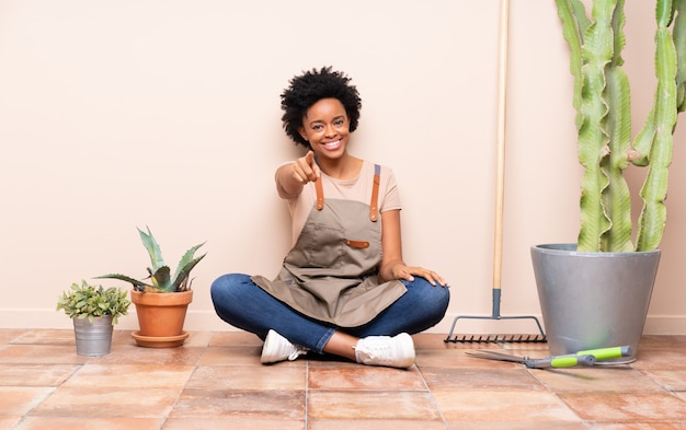 Femme jardinier assis sur le sol parmi les plantes