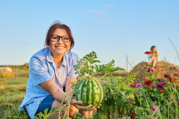 Femme jardinier avec des baies de pastèque dans ses mains sur le jardin de la pastèque