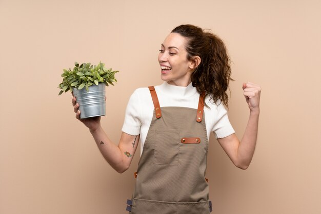 Femme jardinier tenant une plante célébrant une victoire