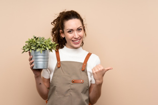 Femme jardinier tenant une plante pointant sur le côté pour présenter un produit