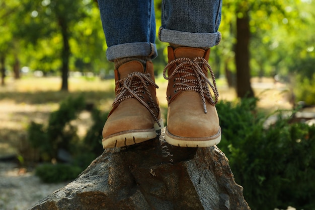 Femme en jeans et bottes debout sur un rocher en plein air