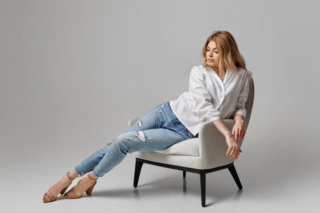 Femme en jeans et une chemise blanche assis dans un fauteuil