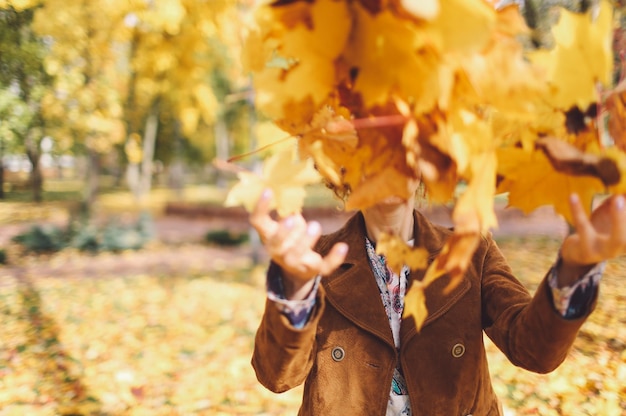 Photo une femme jetant des feuilles d'érable dans le parc