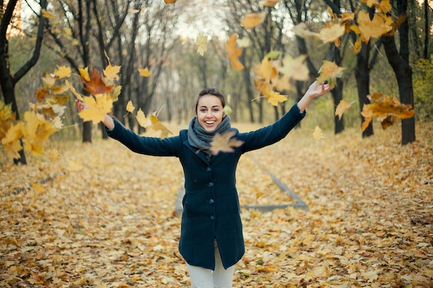 Femme jetant des feuilles jaunes en l'air