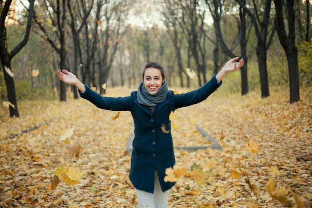 Femme jetant des feuilles jaunes en l'air