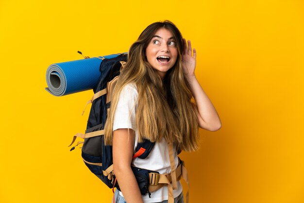 Femme jeune alpiniste avec un gros sac à dos isolé