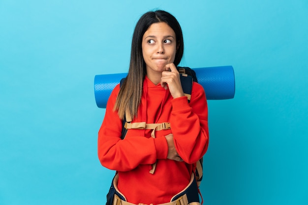 Femme jeune alpiniste avec sac à dos ayant des doutes et de la réflexion