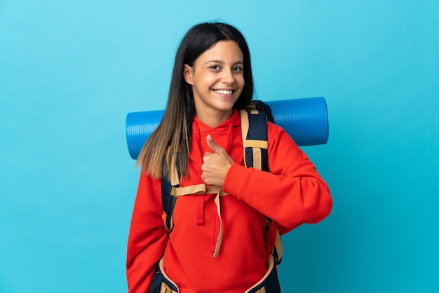 Femme jeune alpiniste avec sac à dos donnant un geste de pouce en l'air