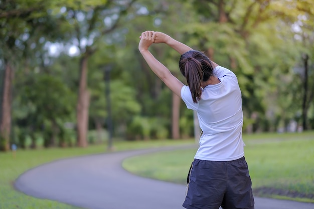 Femme jeune athlète streching dans le parc en plein air