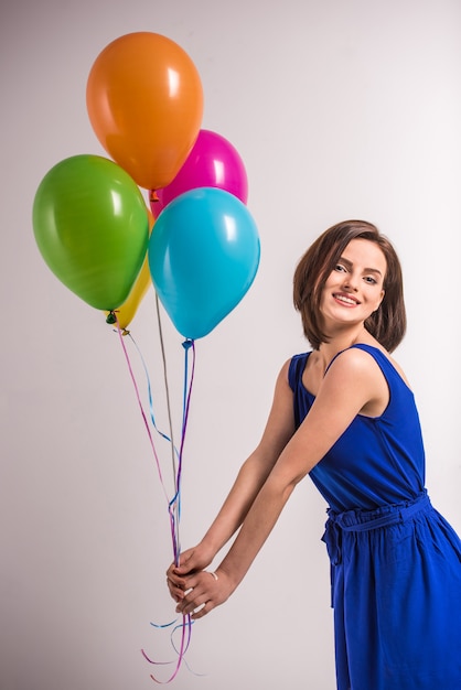Femme jeune beauté souriante tenant des ballons colorés.
