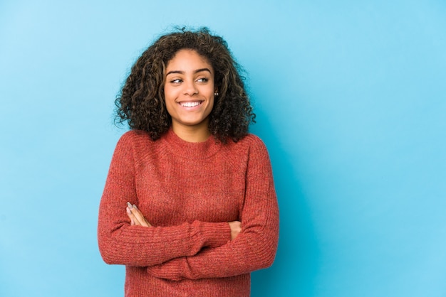 Femme jeune cheveux bouclés souriant confiant avec les bras croisés.