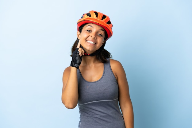 Femme jeune cycliste isolée sur bleu en riant