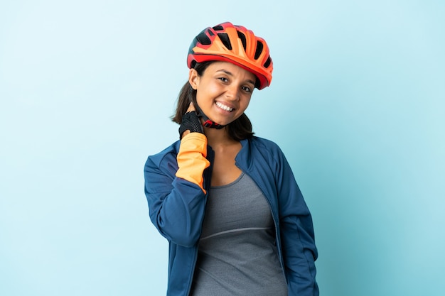 Femme jeune cycliste isolée sur bleu en riant