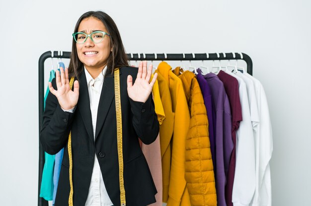 Femme jeune designer asiatique isolée sur blanc rejetant quelqu'un montrant un geste de dégoût.