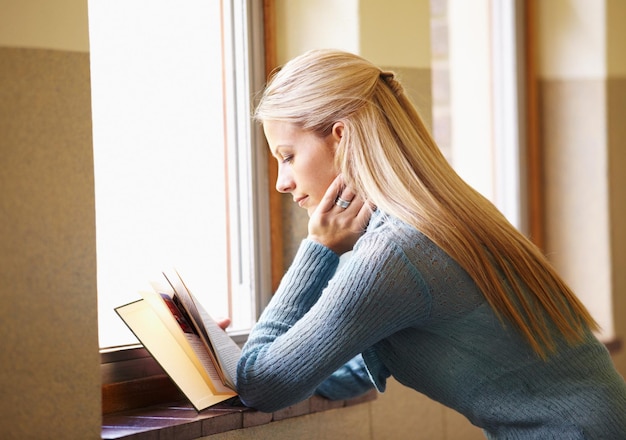 Femme jeune étudiante et lisant un livre ou dans le couloir de l'école ou sur le campus et la fenêtre pour les examens Dame étudiante à l'université et connaissances ou littérature ou salle de classe et projet de test pour information