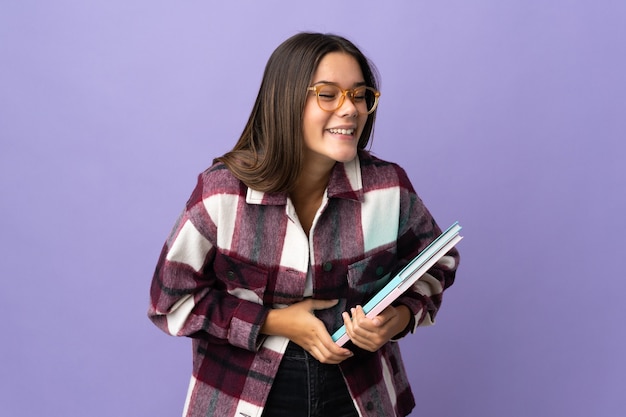 Femme jeune étudiante sur violet souriant beaucoup