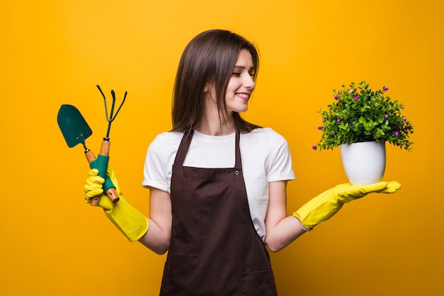 Femme jeune jardinier tenant une plante et des outils