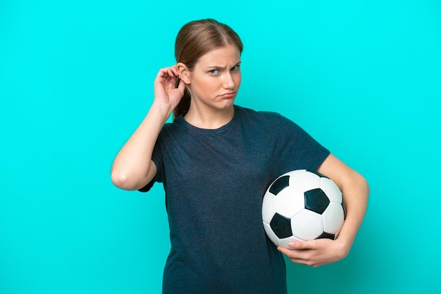 Femme jeune joueur de football isolé sur fond bleu ayant des doutes