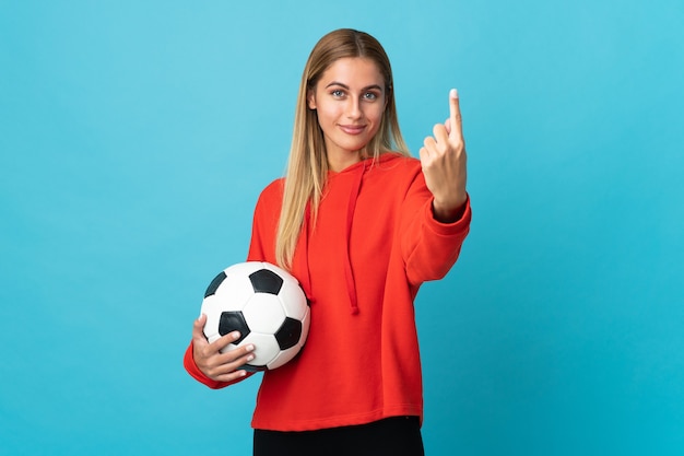 Femme jeune joueur de football isolé sur mur bleu faisant le geste à venir