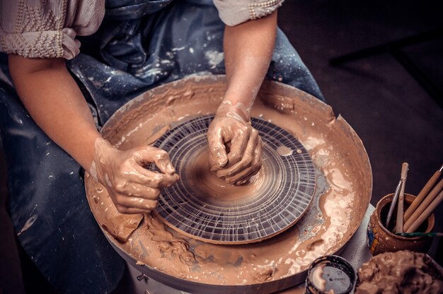 Femme jeune et joyeuse montre comment travailler avec de l'argile et du tour de poterie