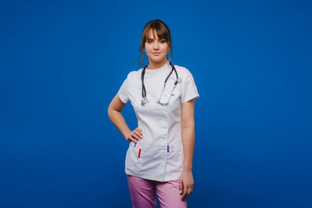 Femme jeune médecin avec stéthoscope isolé sur fond bleu.