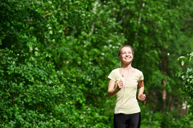 Femme jeune de remise en forme qui court au sentier forestier.