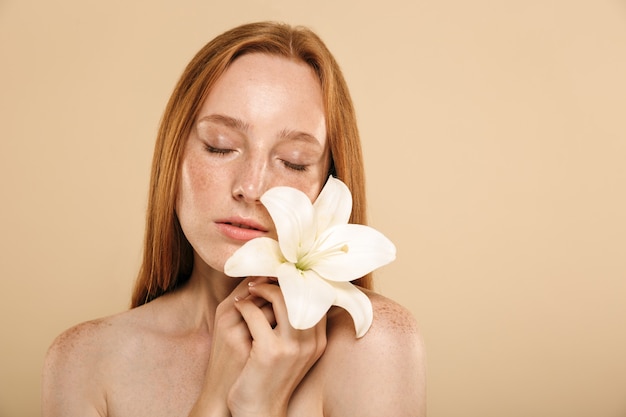 Femme jeune rousse douce tenant une fleur.