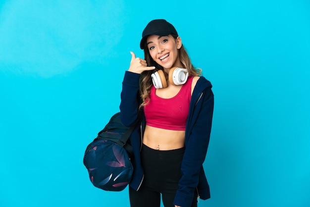 Femme jeune sport avec sac de sport sur bleu faisant le geste de téléphone. Rappelez-moi signe